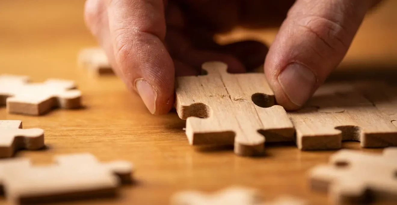 Gros plan sur des mains assemblant minutieusement les pièces d'un puzzle complexe